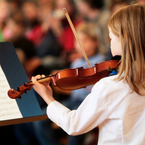 view over a child's shoulder as they play violin at a recital