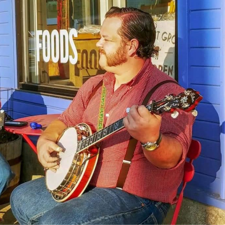 Levi Houston Sanders playing banjo in front of a store window