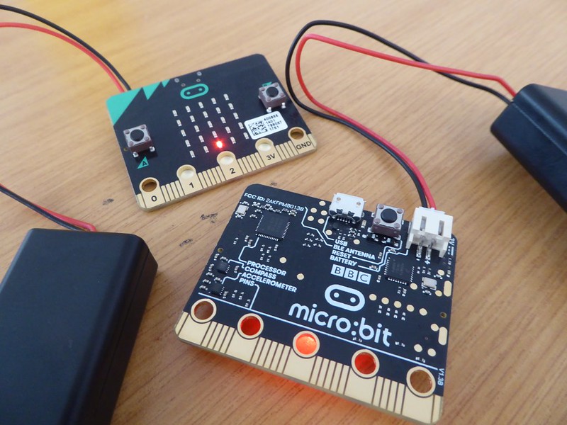 two Micro:bits on a desk with batteries attached.