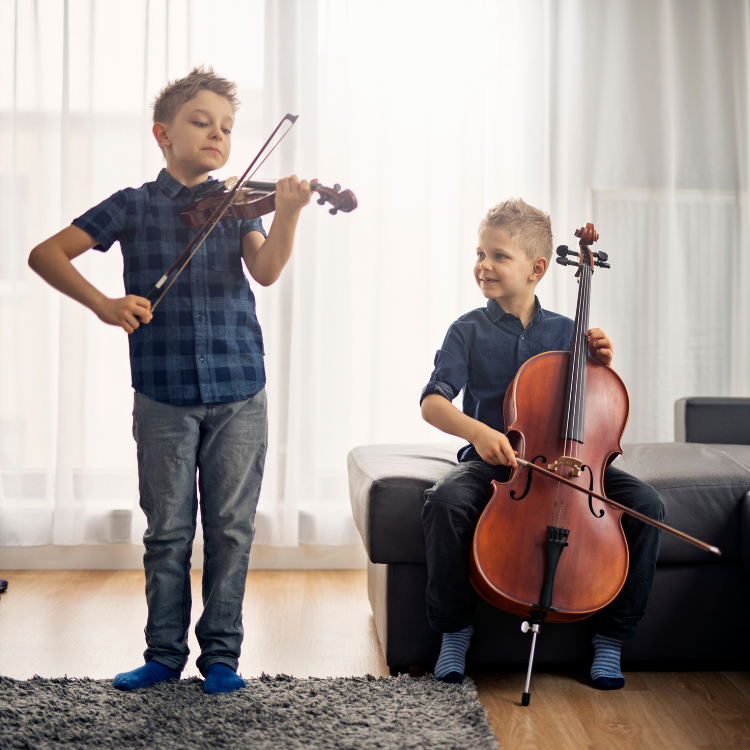 Two brothers smile as they play a cello and a violin together