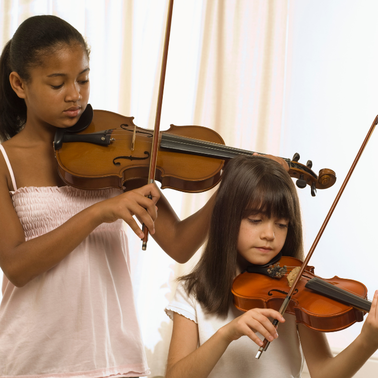 Two girls concentrate while playing violins together