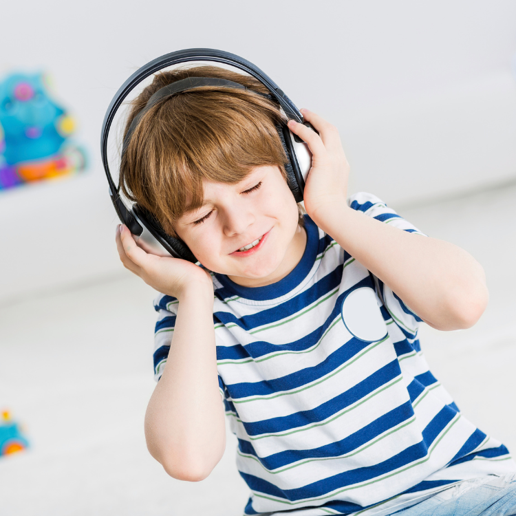 A young boy smiles and listens to music on his headphones